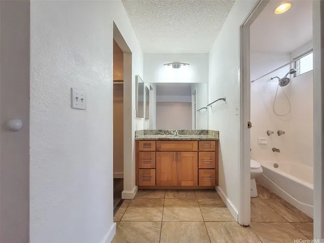 a bathroom with a granite countertop sink mirror and a bathtub