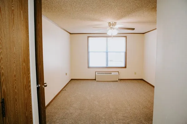 an empty room with chandelier fan and windows