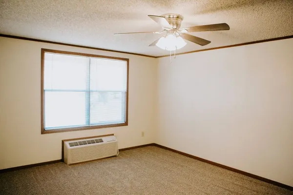 an empty room with a ceiling fan and a window