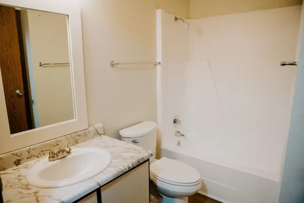 a bathroom with a granite countertop sink toilet and a mirror