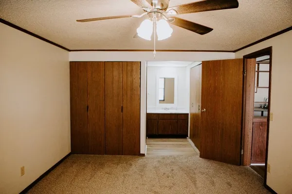 an empty room with closet and a chandelier fan