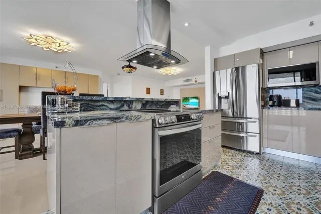 a kitchen with stainless steel appliances a sink a stove top oven a chimney and a center island