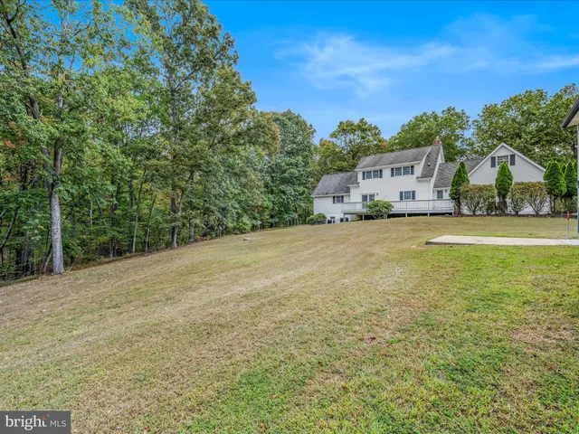 a view of a white house with a big yard and large tree