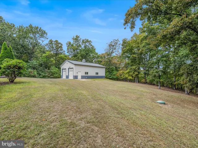 an aerial view of a house with outdoor space and trees all around
