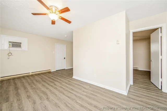 an empty room with wooden floor and a ceiling fan