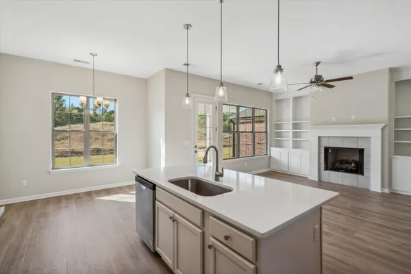 a kitchen with a sink a chandelier stainless steel appliances and wooden floor