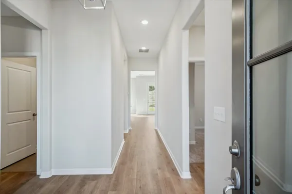 a view of a hallway with wooden floor and a bathroom