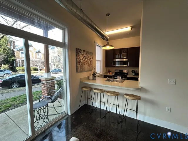 a kitchen with stainless steel appliances granite countertop a stove a refrigerator a sink with wooden cabinets and dining table