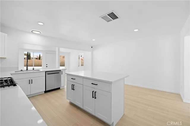 a kitchen with a sink dishwasher stove and white cabinets with wooden floor