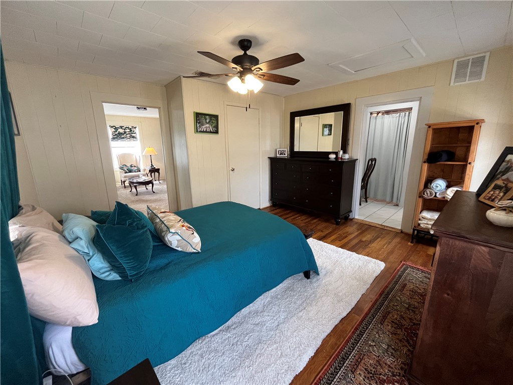 1102 North Travis Avenue Cameron, TX 76520 - Photo 13 of 48 Bedroom with wood finished floors, attic access, a ceiling fan, and wood walls
