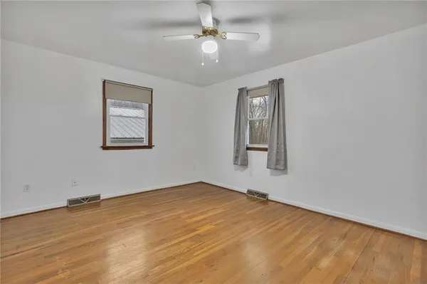 a view of an empty room with window and wooden floor