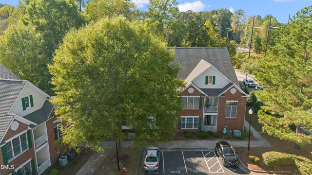 a view of a brick house with a yard and large trees