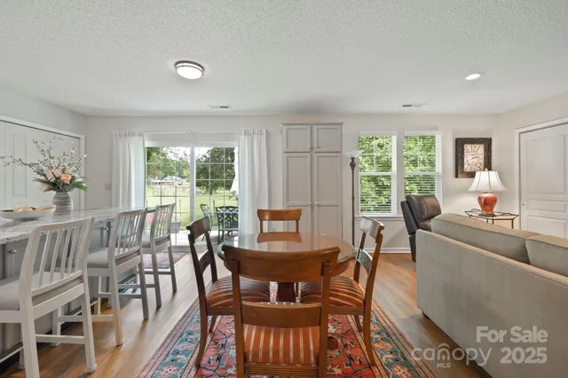 a kitchen with stainless steel appliances granite countertop a stove a sink dishwasher and white cabinets with wooden floor