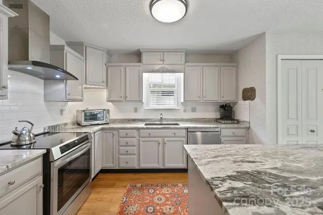 a kitchen with granite countertop white cabinets and a stove