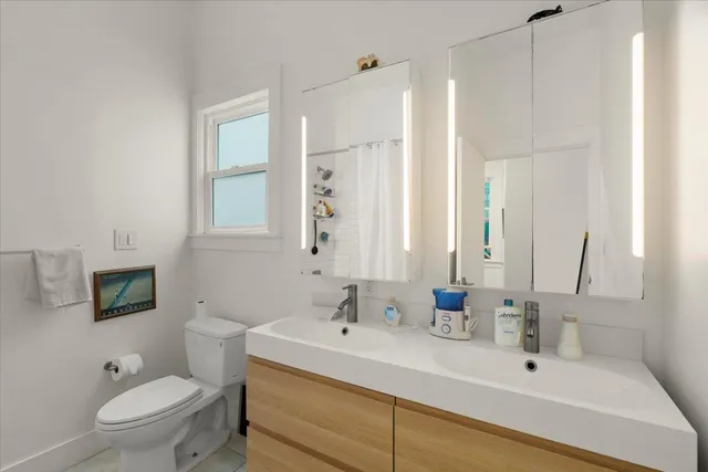 a bathroom with a sink a toilet a mirror and shower
