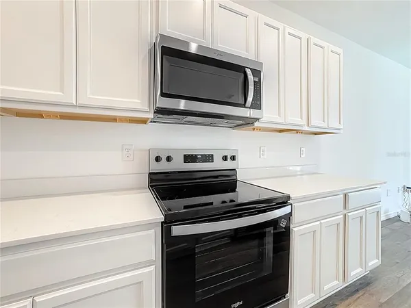 a kitchen with stainless steel appliances granite countertop white cabinets and a stove top oven