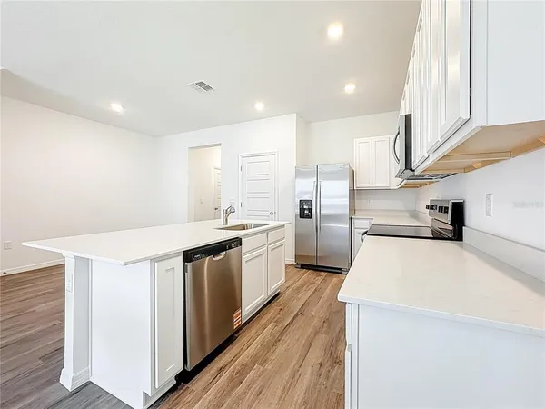 a kitchen with stainless steel appliances a sink a stove top oven a counter space and cabinets