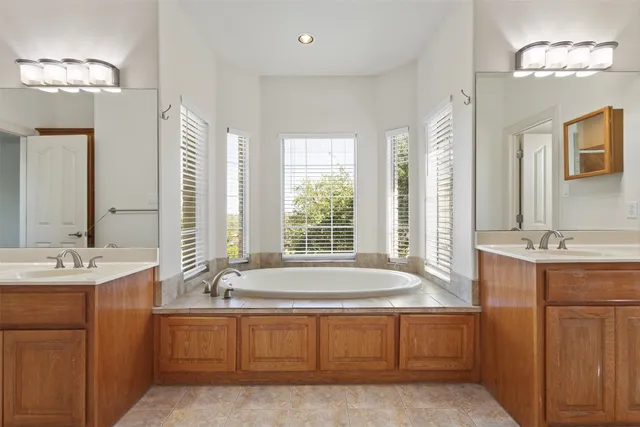 a spacious bathroom with a tub sink and mirror