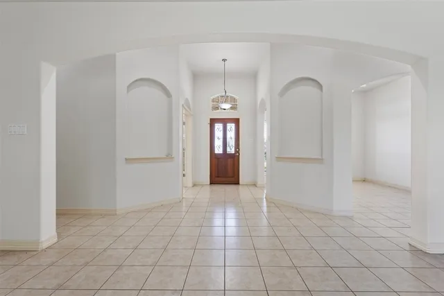 a view of an empty room with window and chandelier fan