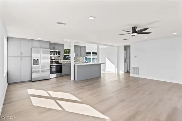 a view of a kitchen with a stove cabinets a ceiling fan and wooden floor
