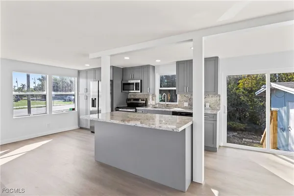 a large kitchen with kitchen island a large counter top space a sink stainless steel appliances and cabinets