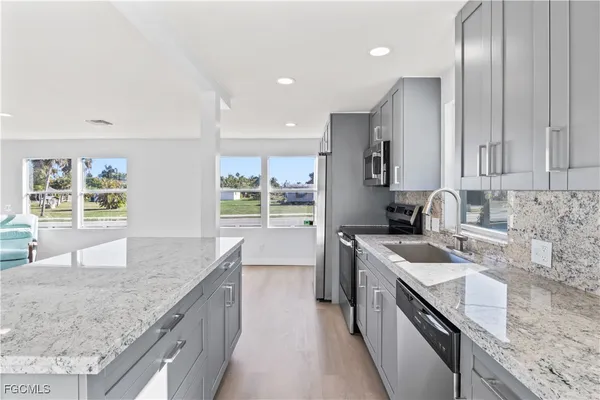 a kitchen with stainless steel appliances granite countertop a sink a stove and a refrigerator