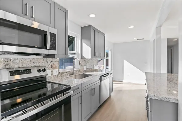 a kitchen with stainless steel appliances a stove microwave and sink