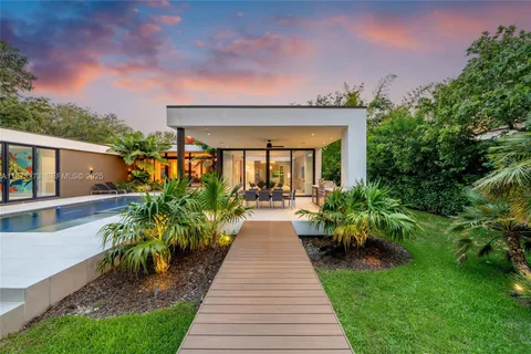 a backyard of a house with plants and large tree