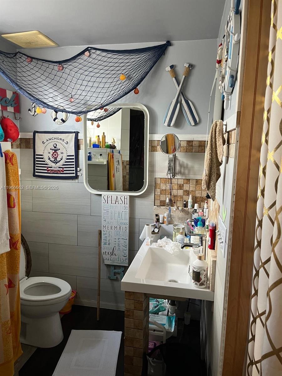 360 South Brida Street Clewiston, FL 33440 - Photo 10 of 14 a bathroom with a sink mirror toilet and shower curtain