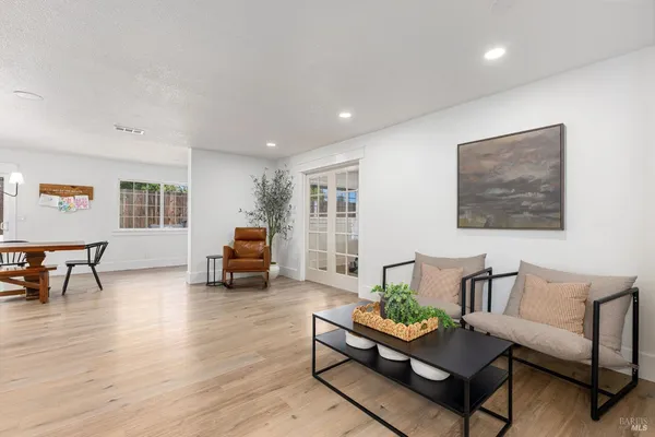 a living room with furniture and a dining table with wooden floor