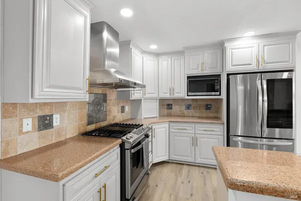 a kitchen with kitchen island granite countertop a sink cabinets and stainless steel appliances