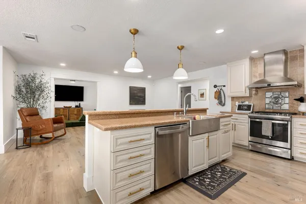 a kitchen with stainless steel appliances kitchen island granite countertop a stove and a view of living room