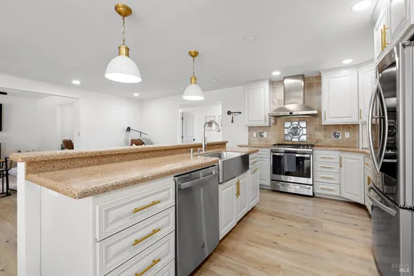 a kitchen with stainless steel appliances granite countertop a sink a stove and a refrigerator