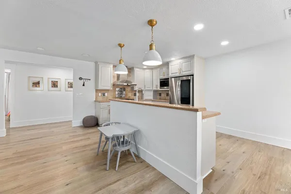 a kitchen with stainless steel appliances a dining table chairs and wooden floor