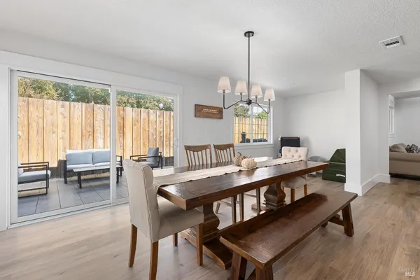 a view of a dining room and livingroom with furniture wooden floor a chandelier
