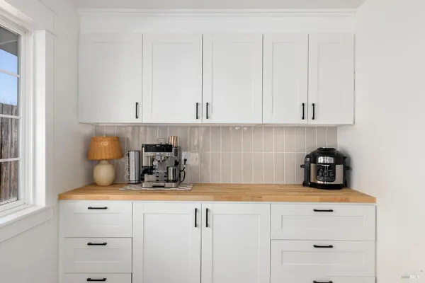 a kitchen with a stove white cabinets and white appliances