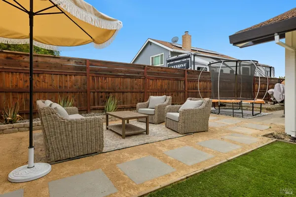 a view of a patio with couches chairs and wooden fence
