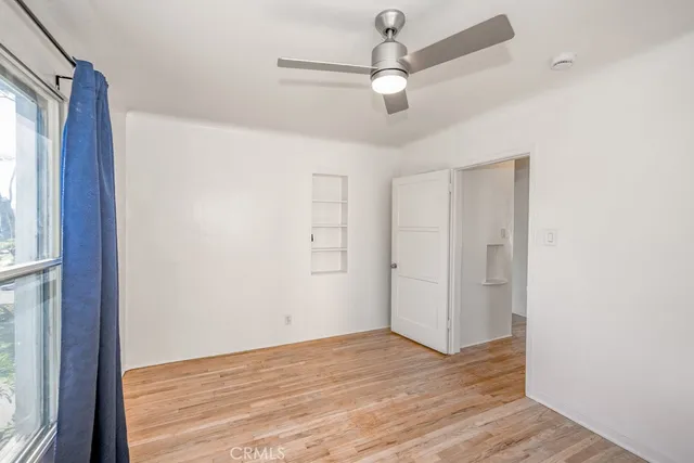 a view of an empty room with wooden floor and a window