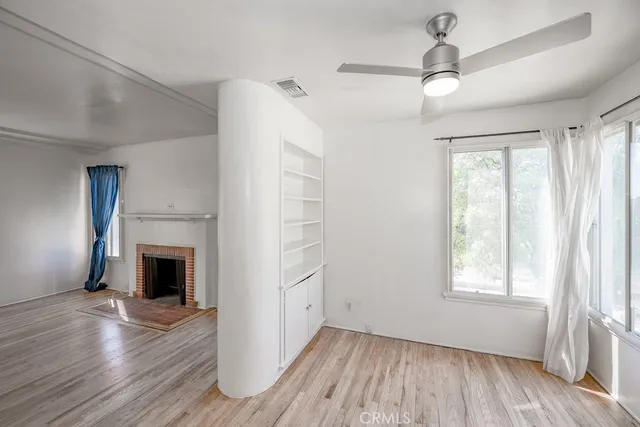 an empty room with wooden floor fireplace and windows