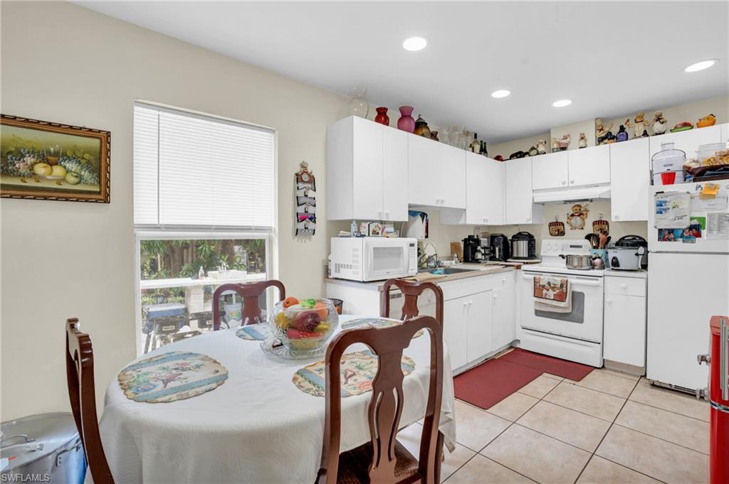2388 55th Terrace Southwest Naples, FL 34116 - Photo 23 of 42 Kitchen featuring sink, white appliances, white cabinetry, and light tile floors