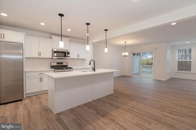 a view of kitchen with stainless steel appliances refrigerator stove microwave and cabinets