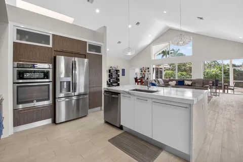 a kitchen with stainless steel appliances kitchen island granite countertop a refrigerator and a sink
