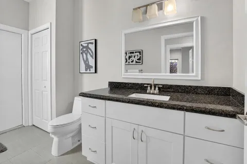 a bathroom with a granite countertop sink and a toilet