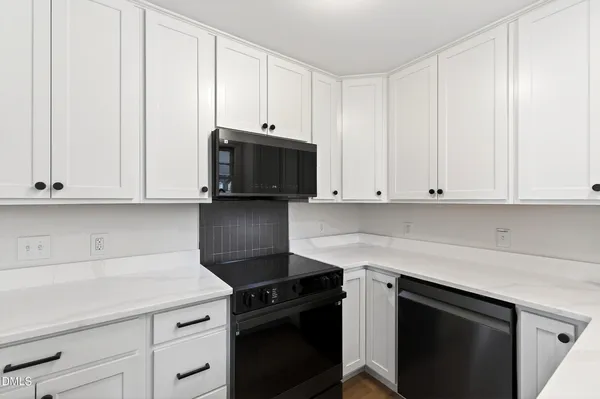 a kitchen with granite countertop white cabinets and black appliances