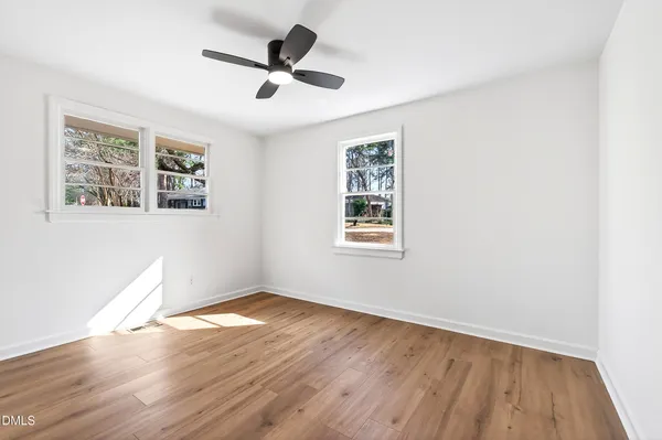 a view of empty room with wooden floor and fan