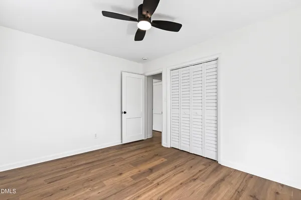 an empty room with wooden floor ceiling fan and window