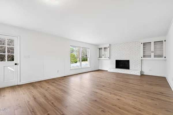 a view of empty room with wooden floor and fireplace