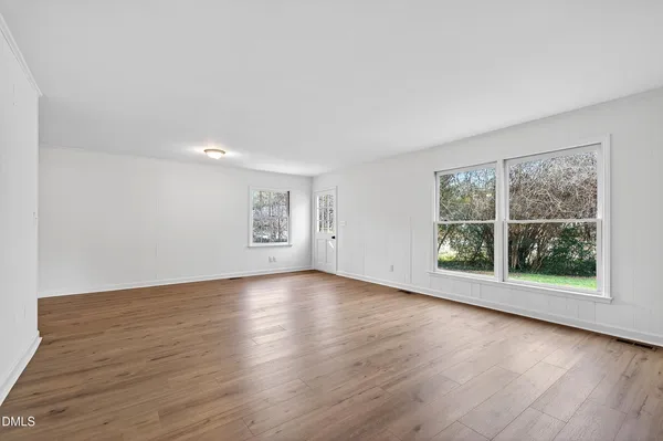 a view of a big room with wooden floor and windows