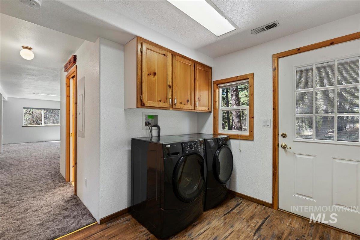 44 Ridgeview Drive Cascade, ID 83611 - Photo 22 of 29 Laundry area featuring a textured wall, a textured ceiling, washer and clothes dryer, cabinet space, and dark wood-style flooring