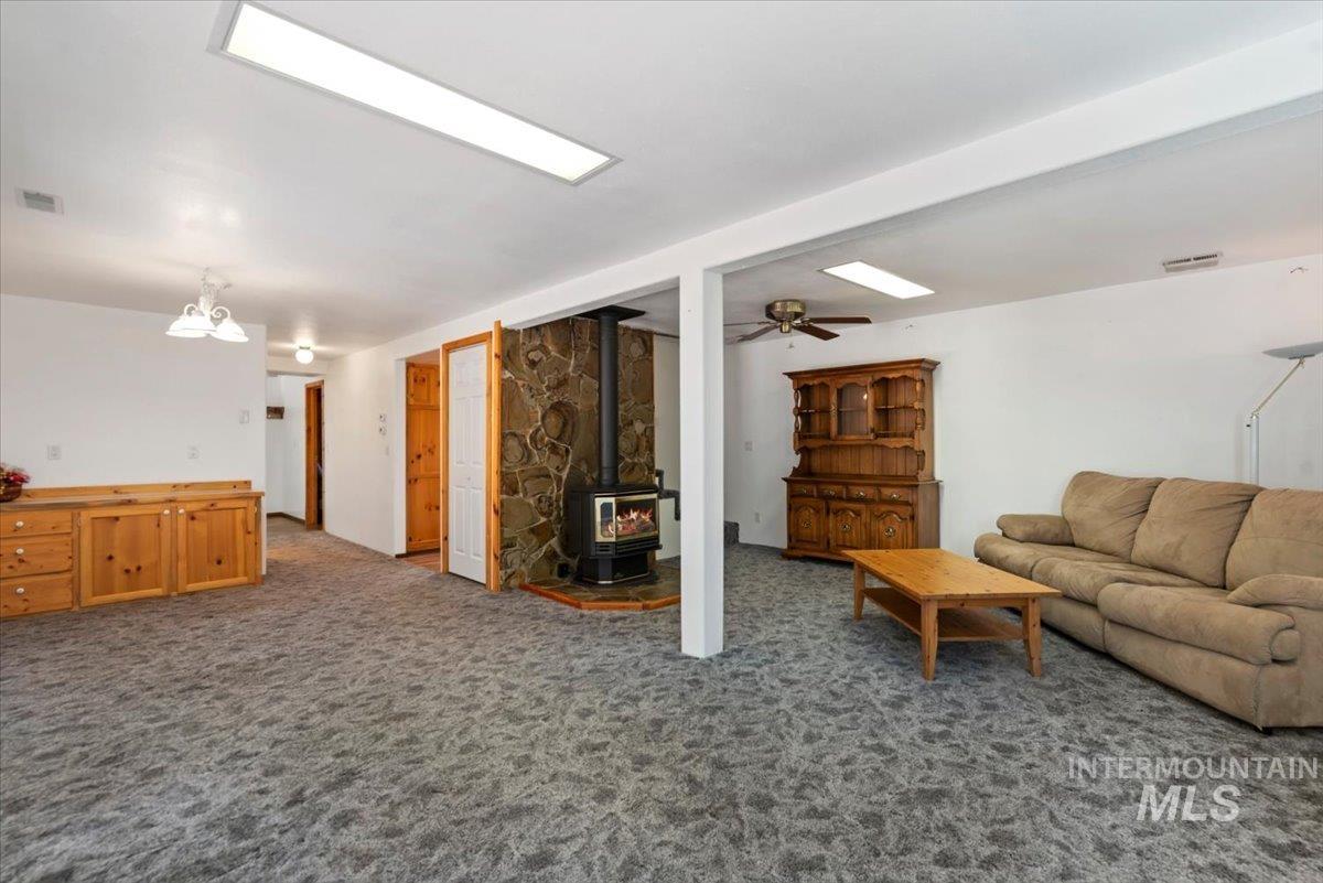 44 Ridgeview Drive Cascade, ID 83611 - Photo 6 of 29 Living room featuring dark colored carpet, a wood stove, and a ceiling fan